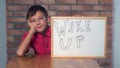 Child sitting at the desk holding flipchart with lettering wake