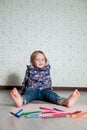 Child sitting on the floor near crayons and paper. Little girl drawing, painting. Creativity concept. Happy, smiling. Royalty Free Stock Photo