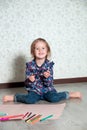 Child sitting on the floor near crayons and paper. Little girl drawing, painting. Creativity concept. Happy, smiling. Royalty Free Stock Photo