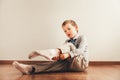 Child sitting on the floor putting on his socks with an expression of effort, concept of autonomy