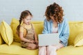 Child sitting near young babysitter working