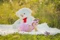 child sitting next to a big teddy bear