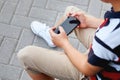 Child sitting outside school and playing games on his cell phone Royalty Free Stock Photo