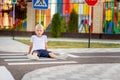 A child is sitting on the road at a pedestrian crossing among road signs, traffic rules for children Royalty Free Stock Photo