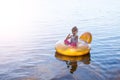 The child is sitting in a rubber ring and talking on a mobile phone and shows a sign approx Royalty Free Stock Photo