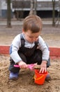 Child sitting in sandbox making mud pie