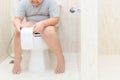 Child sitting in toilet and holding tissue roll