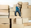 Child sitting on top of heap carton boxes.