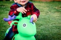 Child sitting on toy cow. Happy smiling child playing on grass Royalty Free Stock Photo