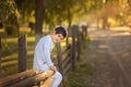 A child is sitting on a wooden fence. Spring time