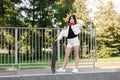 Child with skateboard and headphones. Young girl teenager with skate board stand on sport ramp on skate playground