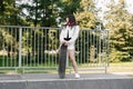 Child with skateboard and headphones. Young girl teenager with skate board stand on sport ramp on skate playground