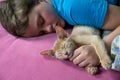 A child is sleeping with a kitten, abyssinian fawn