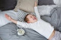 The child sleeps in a bed in gray tones with an alarm clock. Awakening Royalty Free Stock Photo