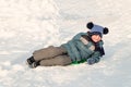 Child slid down a snow slide and is happy lies on an ice-boat Royalty Free Stock Photo