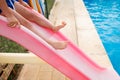 A child slides down a slide into a pool in the summer Royalty Free Stock Photo