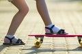 Child slim legs in white socks and black sandals on plastic pink