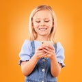 Child, smile and typing with phone in studio for social media, play mobile games and download app on orange background