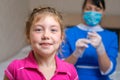 The child smiles on the background of a nurse in a medical mask. The concept of childhood vaccination. The little girl is not Royalty Free Stock Photo