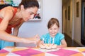 Child smiling watching woman lighting candles on birthday cake Royalty Free Stock Photo