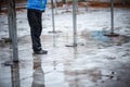 A child in snowboots boots is standing in a puddle of melted snow. Ice on the roads in the city. Not cleaned from snow and ice