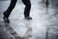 A child in snowboots boots is standing in a puddle of melted snow. Ice on the roads in the city. Not cleaned from snow and ice Royalty Free Stock Photo