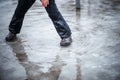 A child in snowboots boots is standing in a puddle of melted snow. Ice on the roads in the city. Not cleaned from snow and ice