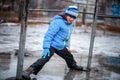 A child in snowboots boots is standing in a puddle of melted snow. Ice on the roads in the city. Not cleaned from snow and ice Royalty Free Stock Photo