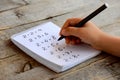 Child solves mathematics examples. Child holds a black marker in his hand. Notebook sheet with multiplication table examples