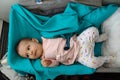 A child in a special cradle on the plane. Top view. Baby look at the side in bassinet lying at green plaid