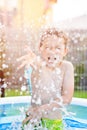 Child splashing water in inflatable garden pool Royalty Free Stock Photo