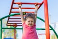 Child and sport. little active emotional girl on playground in park, hanging on horizontal bar, doing sports exercise outdoors.