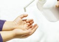 A child sprays her hands with antiseptic from a plastic spray bottle. Hands with a bottle close-up on a white background