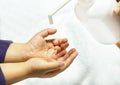 A child sprays her hands with antiseptic from a plastic spray bottle. Hands with a bottle close-up on a white background