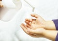 A child sprays her hands with antiseptic from a plastic spray bottle. Hands with a bottle close-up on a white background