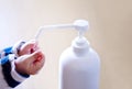 A child sprays her hands with antiseptic from a plastic spray bottle. Hands with a bottle close-up on a blue background