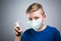 A child sprays a throat with a spray. A child in an antiviral mask