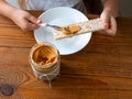 Child eating crispbread with peanut butter on wooden table home kitchen. School girl with bread slice wholegrain snack