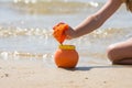 Child sprinkles wet sand from the molds in a pot on the sandy beach seashore