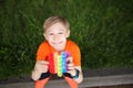 Child squats, looks up and laughs merrily, holding an anti-stress silicone toy balls that burst Royalty Free Stock Photo