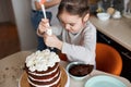 Child squeezing cream from pastry bag on the top of cake