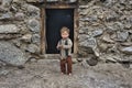 Child standing in front of the house built of stones and yak dung