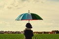 The child, standing under a colored umbrella on the green meadow Royalty Free Stock Photo