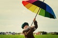 The child, standing under a colored umbrella on the green meadow Royalty Free Stock Photo