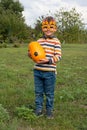 Child stands in field and holds ripe yellow pumpkin in his hands. preschooler boy in glasses with pumpkins shows pumpkin Royalty Free Stock Photo