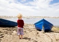 Child Stares Out Over a Bay with Fishing Boats