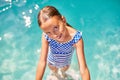 A child on the steps climbing out of the pool, little girl having fun in the swimming pool,