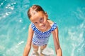 A child on the steps climbing out of the pool, little girl having fun in the swimming pool,