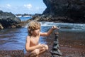 Child and stone tower close up against the ocean. Zen stones on beach for perfect meditation. Sea pebbles tower. Keep Royalty Free Stock Photo