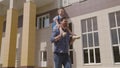 child student with school backpack rides on his father shoulders, dad cheerfully runs with his daughter kid to school